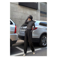 Woman wearing high waist wide leg draped trousers in black
